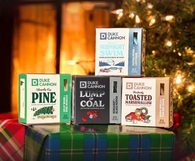 Four Duke Cannon holiday pucks on a festive background.